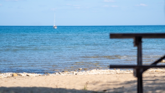 A view of a sailboat in the water from the beach