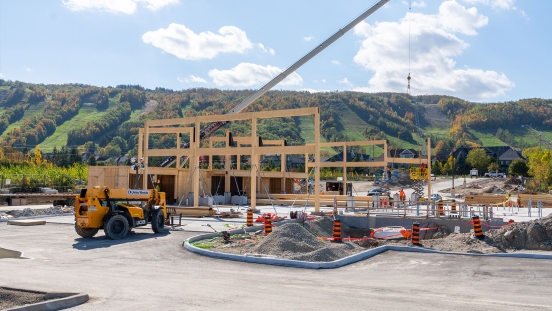 Crane lifting mass timber beams into place on structure with Escarpment in background