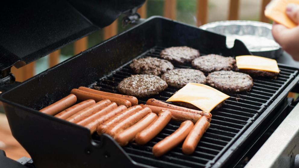 BBQ with hotdogs and hamburgers cooking