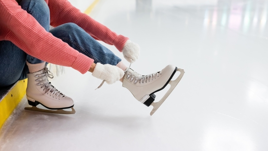 Person sitting and lacing up figure skates