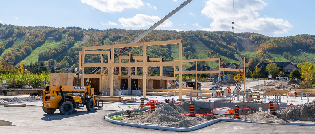 Crane lifting mass timber beams into place on structure with Escarpment in background