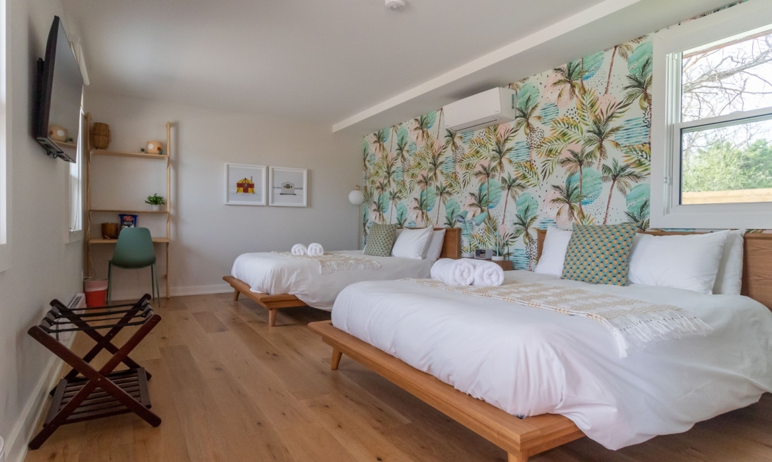 Interior of room with two beds and colourful wallpaper.