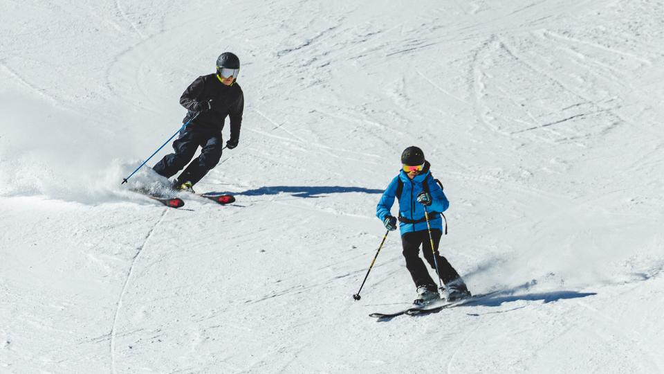 Two skiiers on a groomed slope