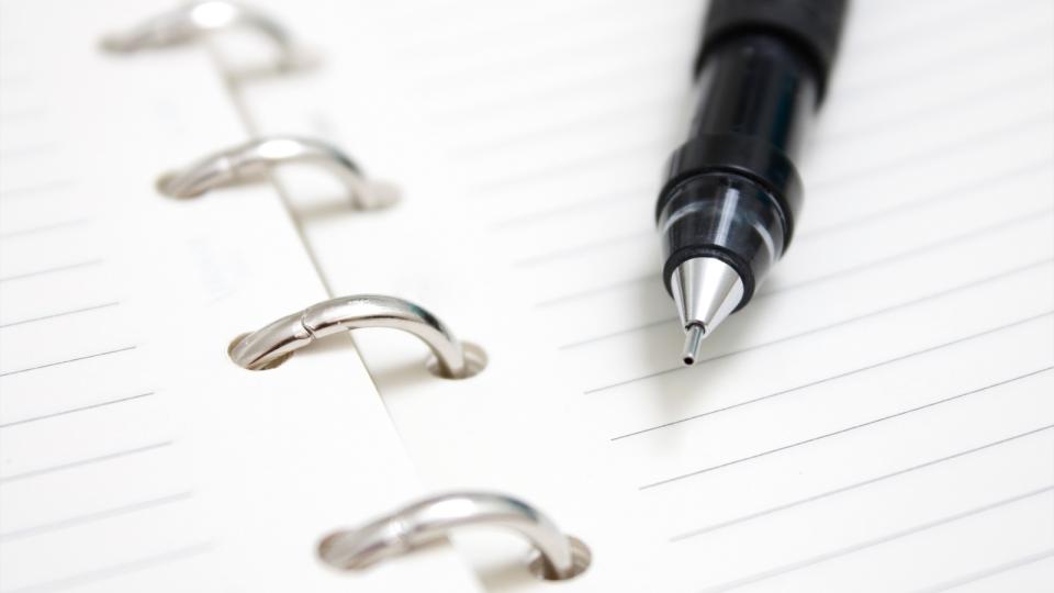 Pen laying on blank notepad