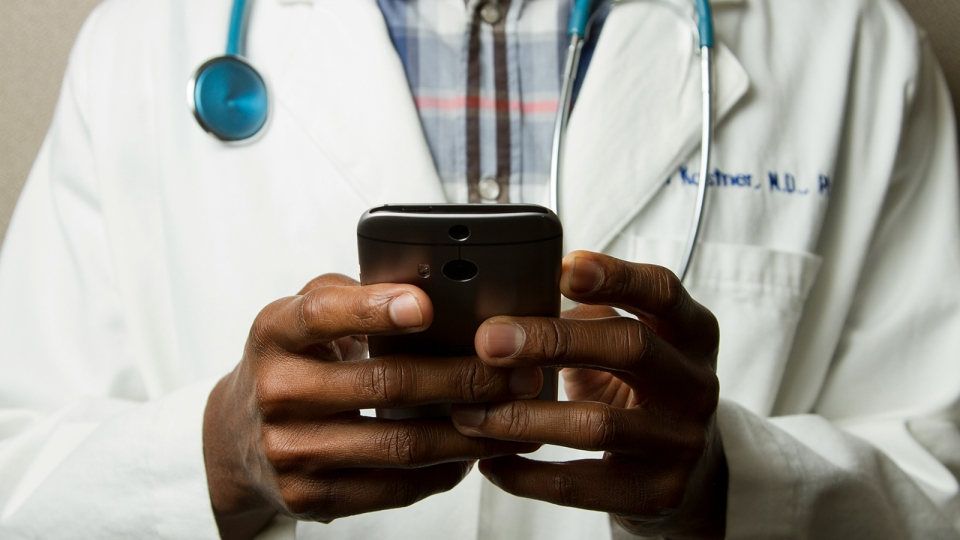 Hands of a doctor holding a cell phone